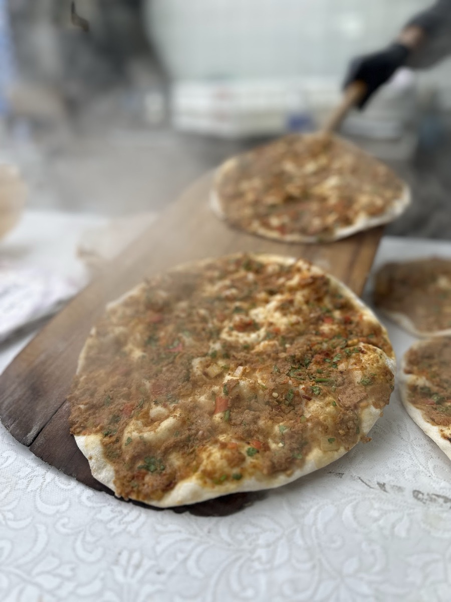 Lahmacun sortant du four sur une pelle en bois